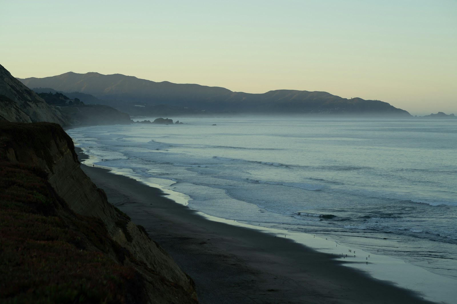 Coastal cliffs and ocean waves at dusk